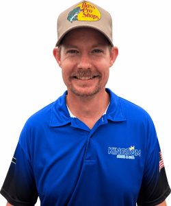 Man in a blue "Kingdom Fencing & Grading" polo shirt and Bass Pro Shops hat, smiling at the camera.