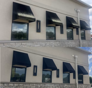 A commercial building exterior with black metal window awnings and modern wall lighting.