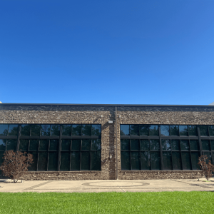 Exterior of a modern industrial-style building under a bright, cloudless blue sky.
