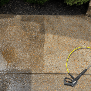 A pressure washer cleaning a concrete sidewalk, showing a clear difference between the cleaned and dirty sections.