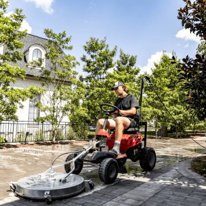 A professional exterior cleaning technician operating a ride-on pressure washing surface.
