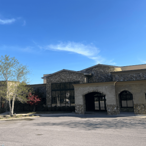 Stone building with arched entrance reading "Chabad of Nashville" under a clear blue sky with a tree nearby.