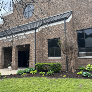Exterior entrance of a large brick church building identified as First Baptist Church.